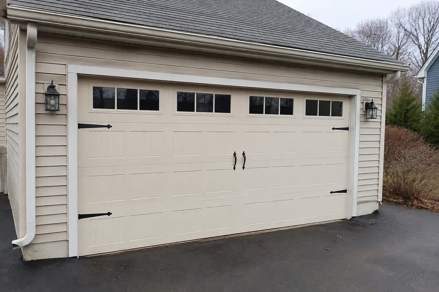 Cream carriage-house-style garage door with dark decorative hardware. — Carriage-House Garage Door Installation, Oshawa